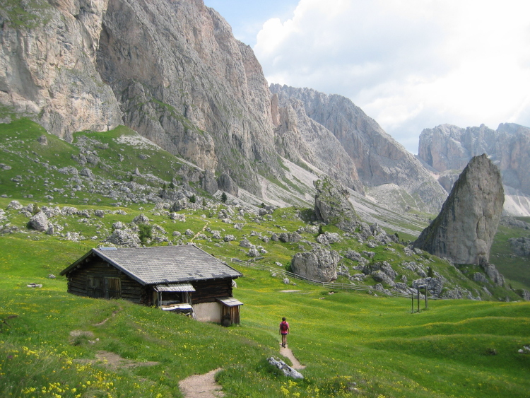 Una baita sull'Alta via di Cisles. Nel prato sotto gli strapiombi ci sono pezzi di roccia ovunque, grandi e piccoli.