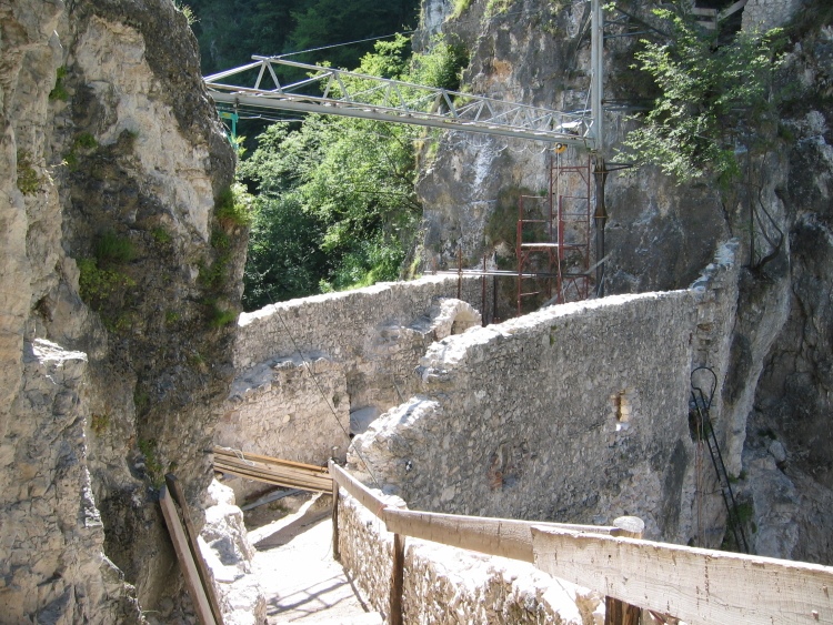 Il camminamento nella cinta muraria sovrastato da una piccola gru e accompagnato da un parapetto provvisorio fatto di assi di legno.