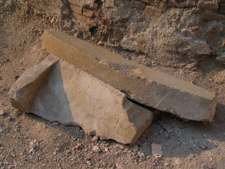 Due pezzi di pietra abbandonati. Sono pietre storiche con forme rotondeggianti e ad arco.