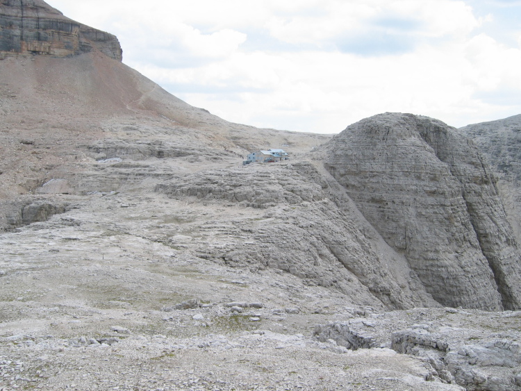 Riprendiamo il cammino ancora lungo. Il sentiero continua con dei saliscendi. Nella foto il rifugio Boè visto dall'altra parte. Sulla sua destra un dosso roccioso molto arrotondato. Più a destra ancora la caduta nella valle interna.