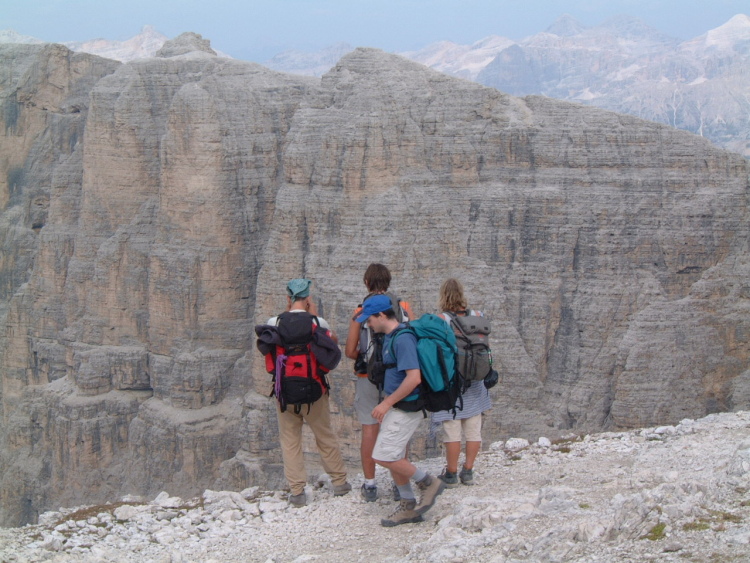 Tre amici ammirano la valle stando in piedi vicino al precipizio. Io sto passando dietro di loro.