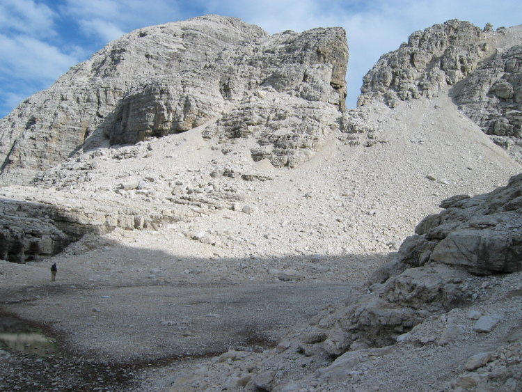 Un amico cammina nella valle circondato dalle vette, giganti confronto a lui.