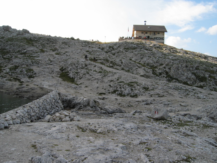 Il rifugio visto dal lago e l'ultimo pezzo di sentiero sulle rocce.