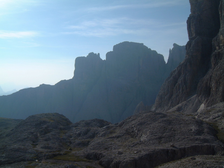Le montagne della Val Gardena in controluce con un effetto nebbia. In primo piano le rocce vicine - sta diventando buio.