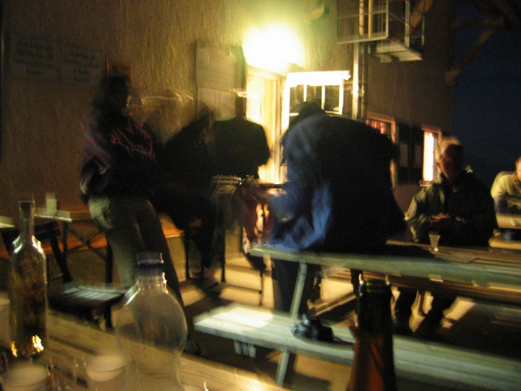 Un gruppo di persone ha portato una chitarra. Intonano canzoni sui tavoli all'esterno del rifugio.