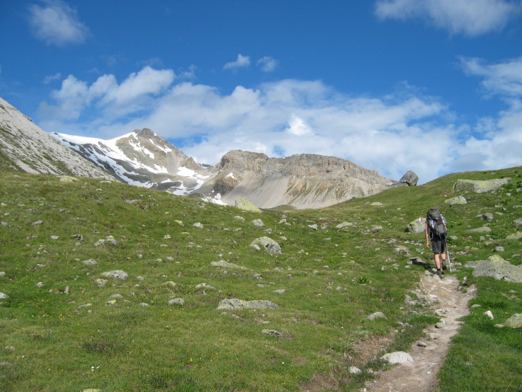 Il mio compagno di escursione s'incammina lungo il primo tratto di sentiero. Sullo sfondo le cime innevate.