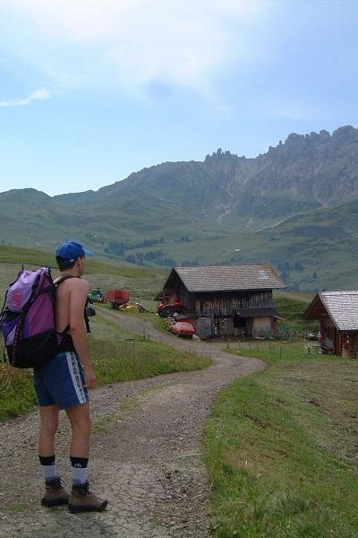 Me stesso sul sentiero vicino ad alcune casette di legno. Sullo sfondo i Denti di Terrarossa in lontananza.