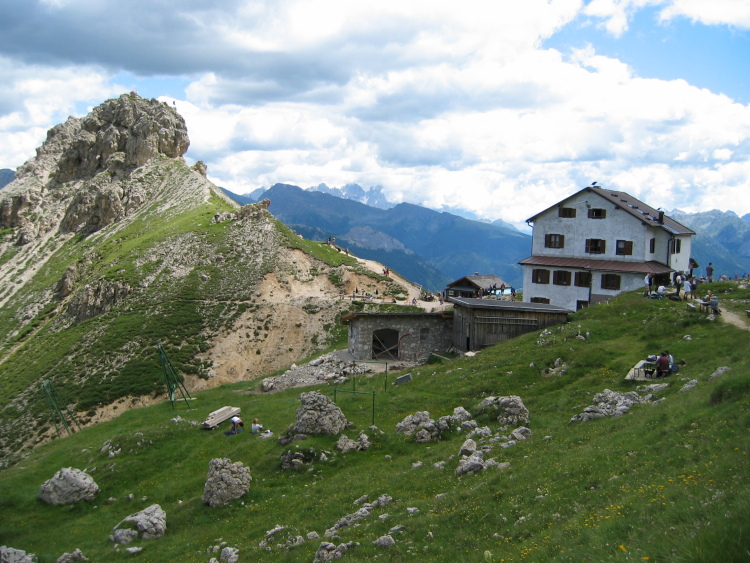 I due rifugi sono molto vicini tra loro. Sulla sinistra vediamo un dosso con la cima di roccia, il Ciampac. C'è molta gente.