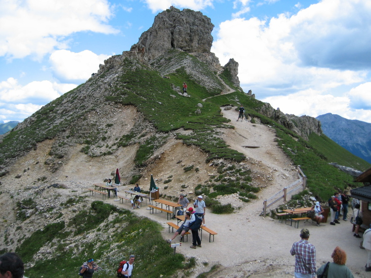 Il Ciampac è un dosso sassoso a punta e si trova vicino ai due rifugi Roda di Vael e Pederiva. C'è chi sale, chi scende e chi siede ai tavoli all'inizio del sentierino di salita.